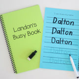 Laminated dry erase book for preschool through kindergarten age children. This image shows two different book color options of blue and green. The books are personalized with the childs name and has a spot for children to practice writing their name